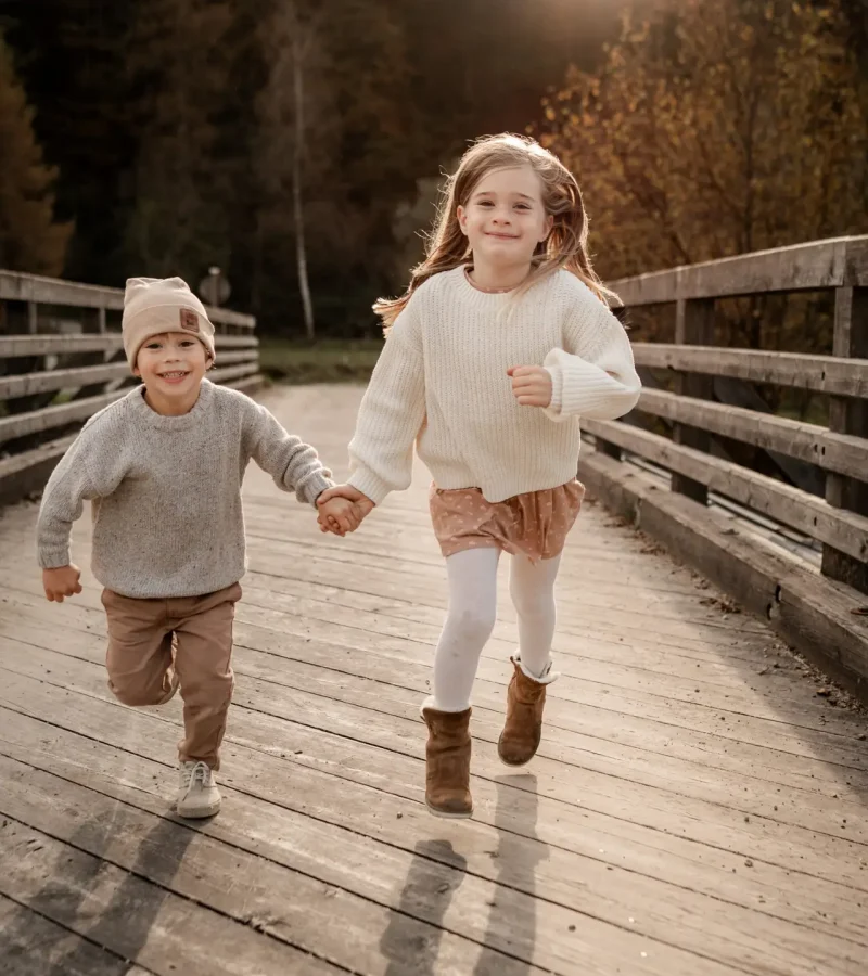 a boy and girl running on a bridge